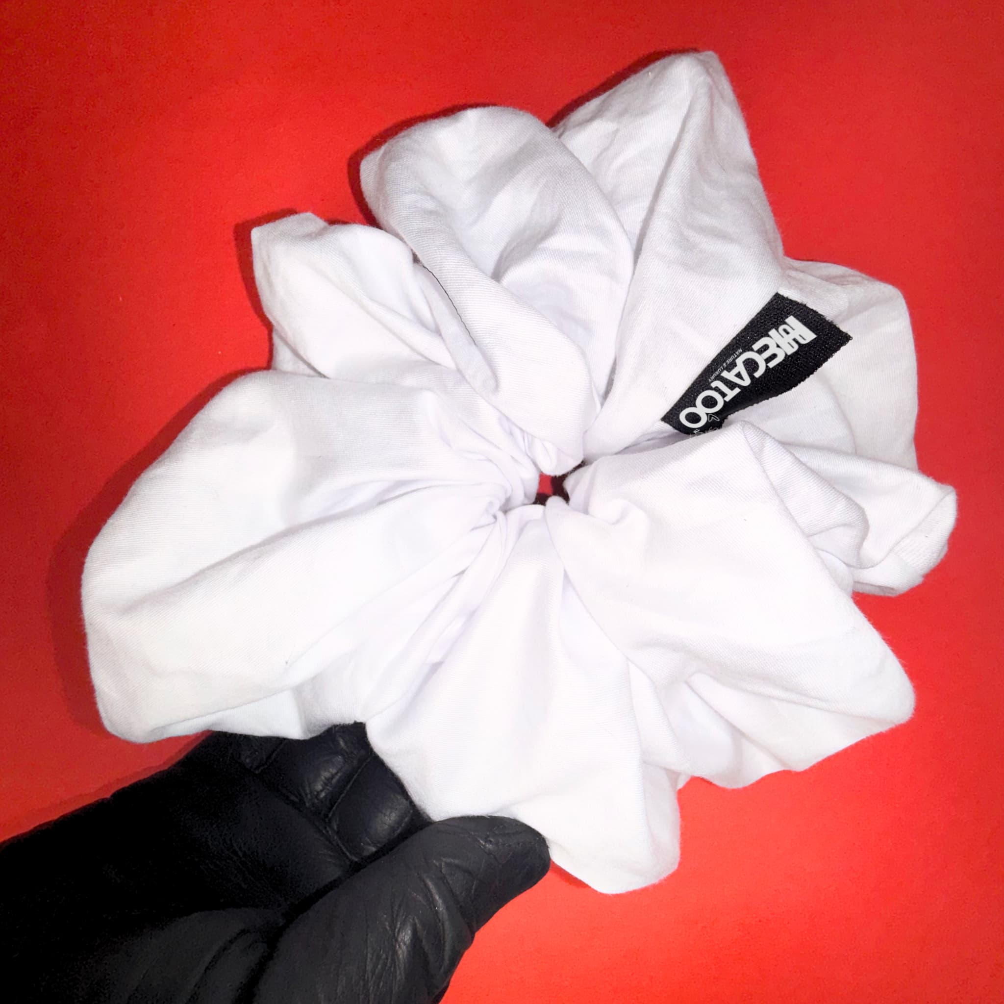 Scrunchie Maxi bílá od Hecatoo™ v ruce – ukázka skutečné velikosti největší gumičky v kolekci. Ručně šitá v české dílně ze 100% bavlněného saténu certifikovaného Öko-Tex Standard 100 tř. I.