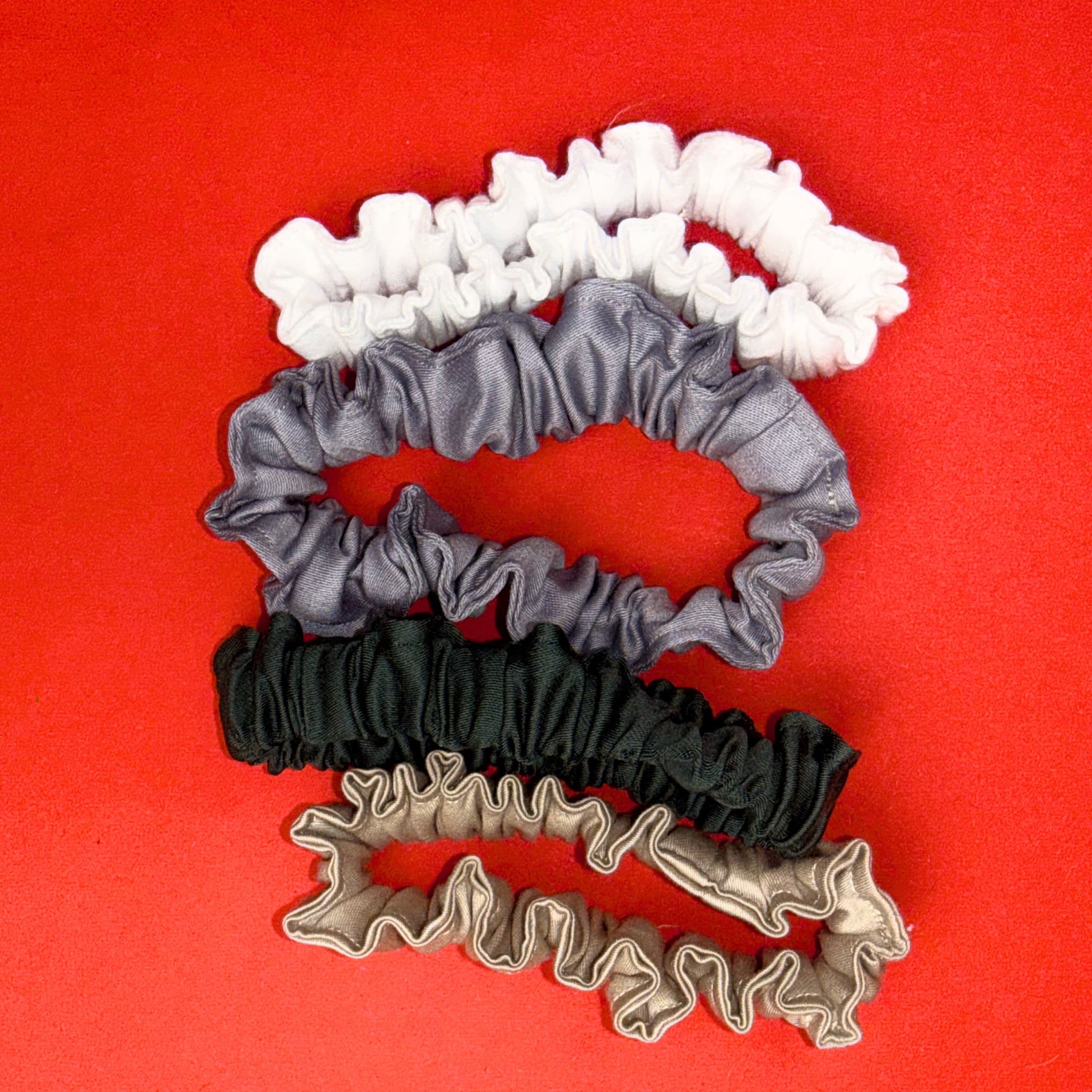 Scrunchie Mini Hecatoo™ ve čtyřech barvách – bílá, šedá, smaragdová a béžově zlatá. Handmade gumičky do vlasů z bavlněného saténu certifikovaného Öko-Tex Standard 100.