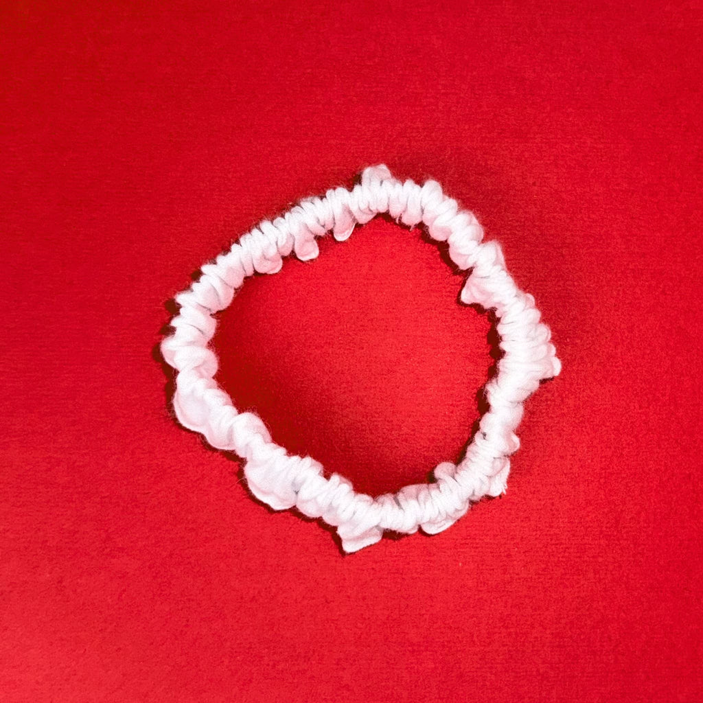 Detail bílé Scrunchie Mini od Hecatoo™ — kompaktní gumička ze 100% bavlněného saténu certifikovaného Öko-Tex Standard 100. Vyrobeno v EU.