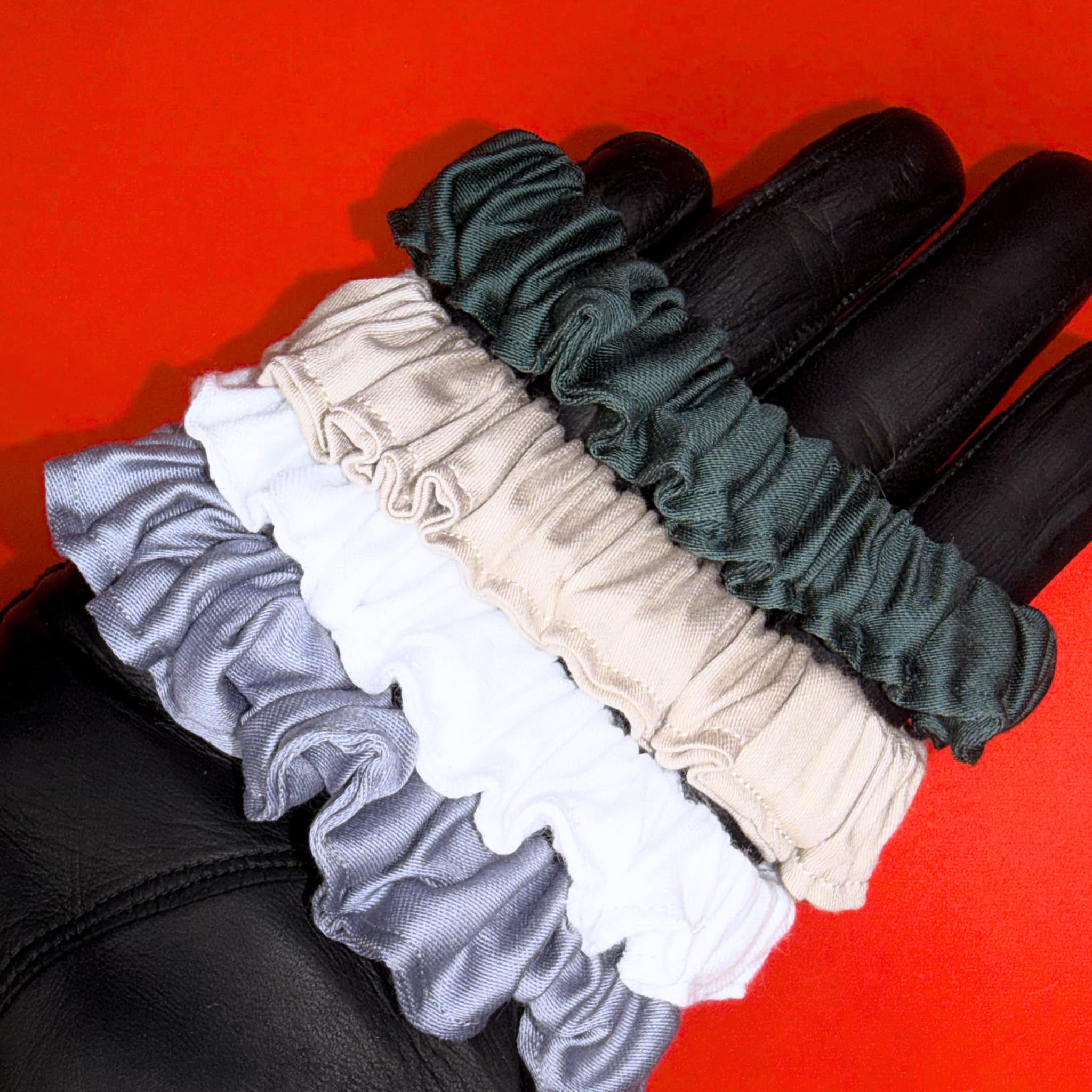 Scrunchie Mini od Hecatoo™ ve všech čtyřech barvách nasazené na ruce jako náramky – šedá, bílá, béžově zlatá a smaragdová. Gumička do vlasů i elegantní doplněk na zápěstí.