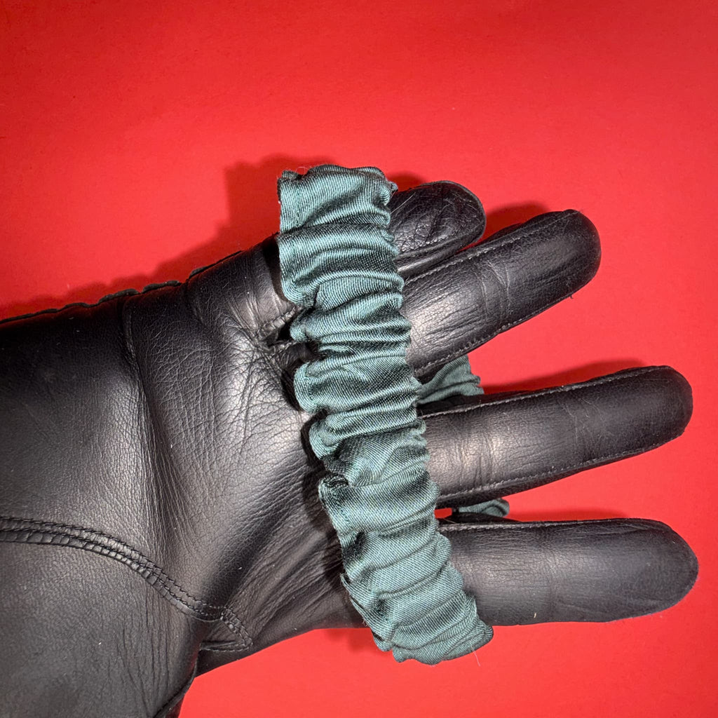 Detail smaragdové Scrunchie Mini od Hecatoo™ na ruce – jemné řasení z bavlněného saténu které nepoškozuje vlasy ani pokožku. Ručně šitá v české dílně, žádný syntetický materiál.