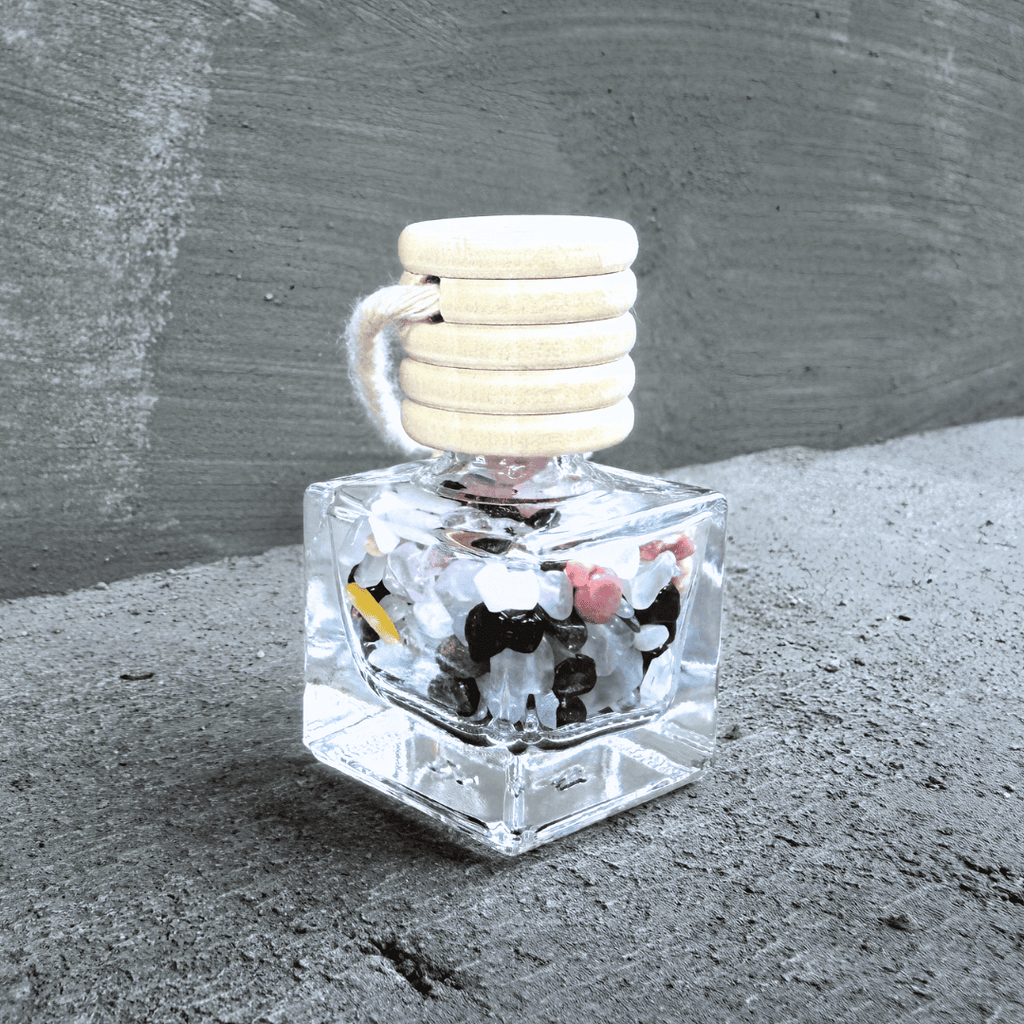 Detailní pohled na talisman Hecatoo Láska z minerálů granát, růženín, ametyst, měsíční kámen a rodonit ve skleněné lahvičce s provázkem.