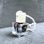 Detailní pohled na talisman Hecatoo Ochrana s obsidiánem, tygřím okem, křišťálem, onyxem a labradoritem ve skleněné lahvičce s provázkem.