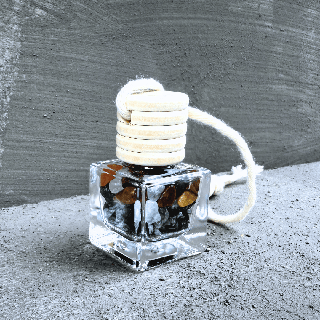 Detailní pohled na talisman Hecatoo Ochrana s obsidiánem, tygřím okem, křišťálem, onyxem a labradoritem ve skleněné lahvičce s provázkem.